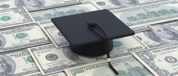 Graduate cap lying atop one-hundred-dollar banknotes