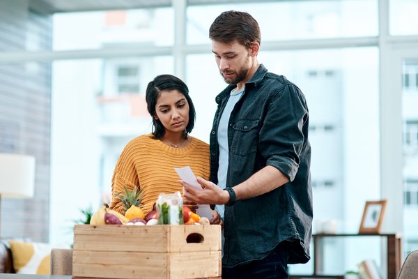 People looking surprised at receipt with food in box.