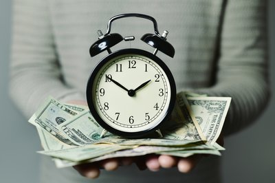 Alarm clock sitting atop a pile of cash.