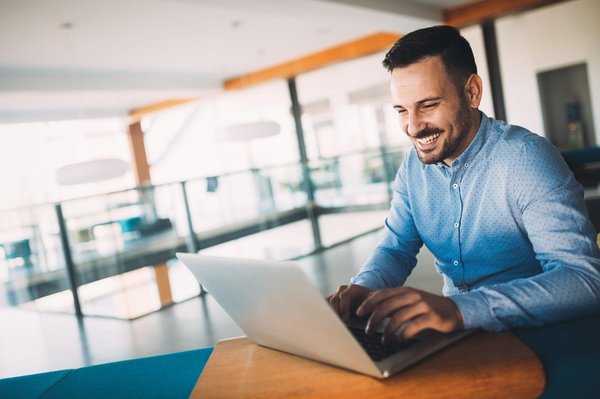 Young man smiles and works on his laptop