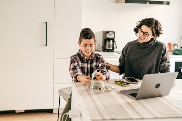 An adult and child working on finances at home.