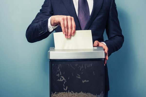 Headless person in tie shredding paper.