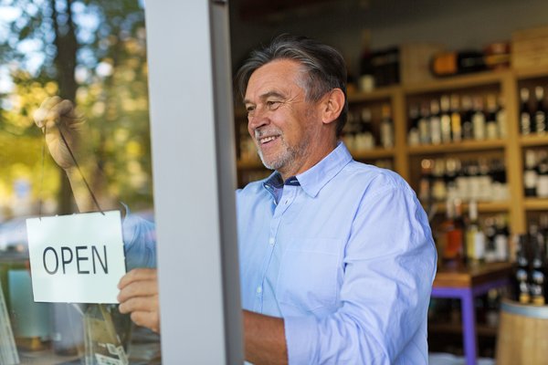 Man putting Open sign in store window.