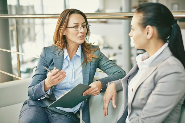 Two women in business suits talking.